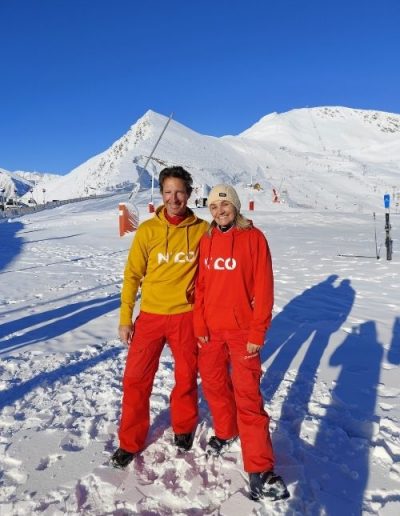 Couple portant des sweats N’CO moutarde et rouge en montagne