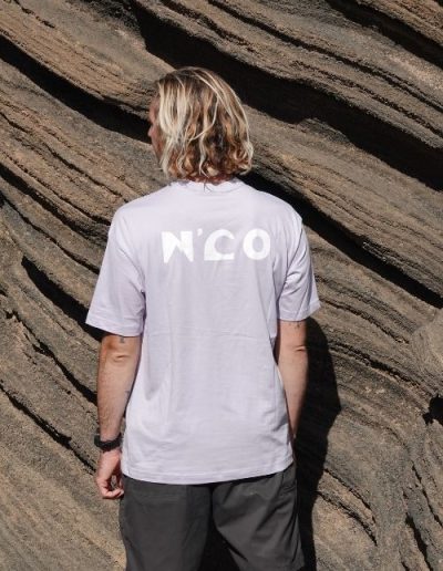 Femme portant un t-shirt gris N’CO de dos face aux rochers sur la plage collection N’CO Lannemezan